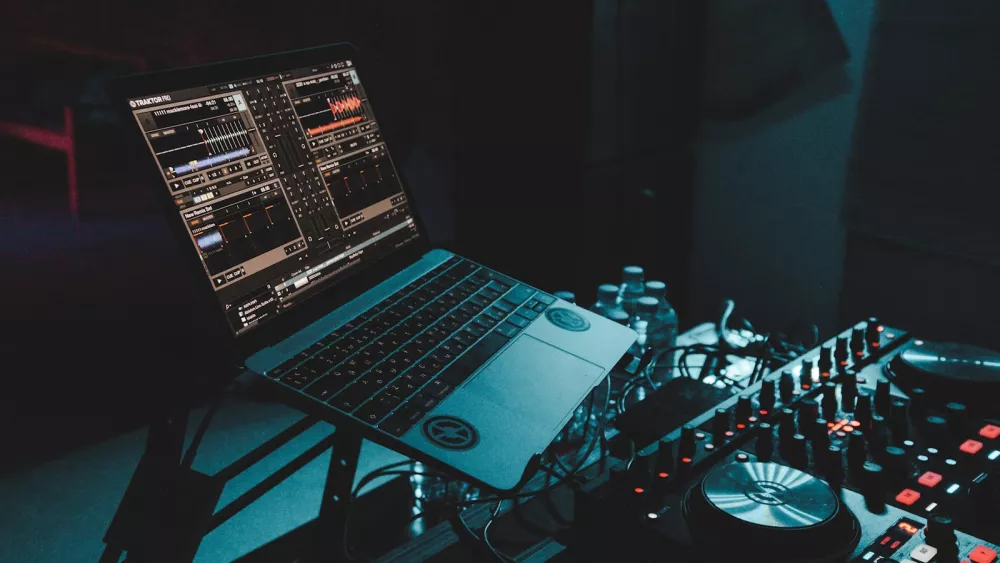 Laptop sitting on top of a DJ mixing desk