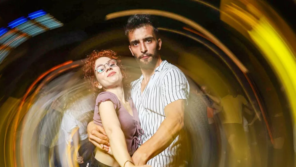 A couple dancing close in a dimly lit club, captured with motion blur