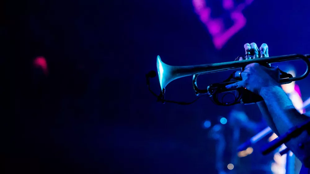 A trumpeter playing under warm stage lights at a live show