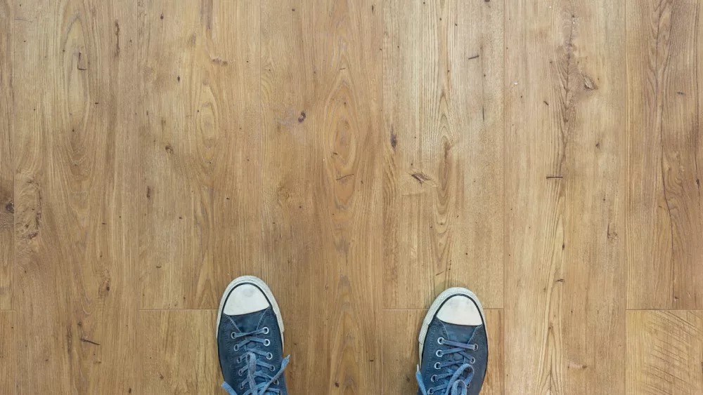 Two blue canvas sneakers seen from above on a light wooden floor