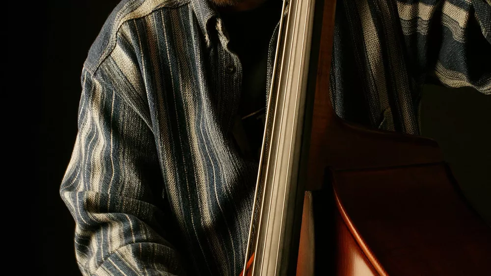 Musician playing an upright double bass in a dark studio setting